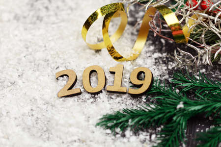 Wooden text numbers on the snow with a Christmas tree and a golden serpentine on the eve of the New Year's holiday in winterの写真素材