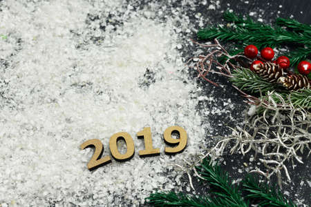 Wooden text numbers on the snow with a Christmas tree and a golden serpentine on the eve of the New Year's holiday in winterの写真素材