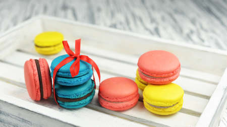 macaroons sweet tasty cookies with red bow French almond with cream on bright white wooden backgroundの写真素材