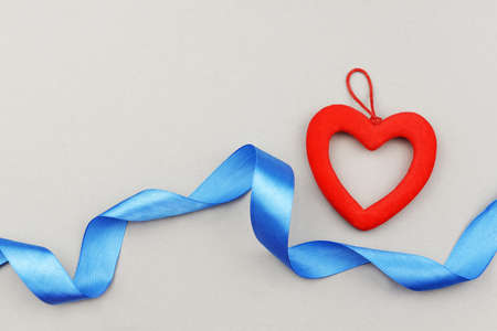 heart decoration red with a blue ribbon bow on a gray background for the holiday Valentine's Day March 8 Mother's Dayの写真素材