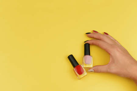 girl holding trendy bottles with gel varnish red for female nails on a yellow backgroundの写真素材