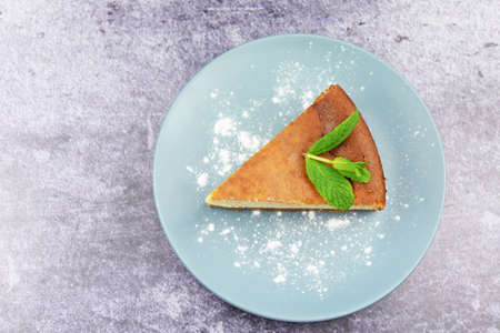 top view on a delicious cream cheesecake tart pie with a leaf of mint on a plate on a dark backgroundの写真素材
