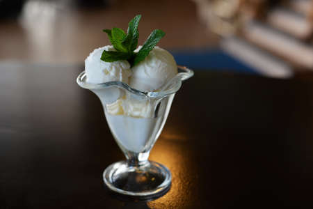 balls of dairy ice cream in a beautiful glass with a sprig of mint in a restaurant