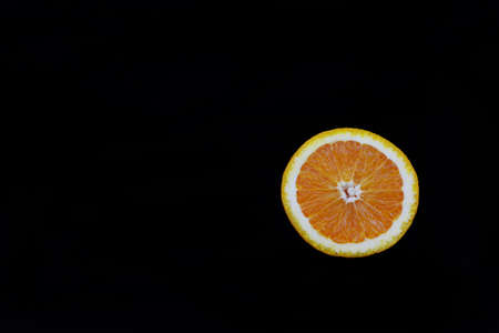 half ripe orange fruit useful on an isolated black backgroundの写真素材