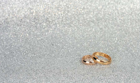 gold wedding rings for newlyweds on a silver background with bokeh closeup