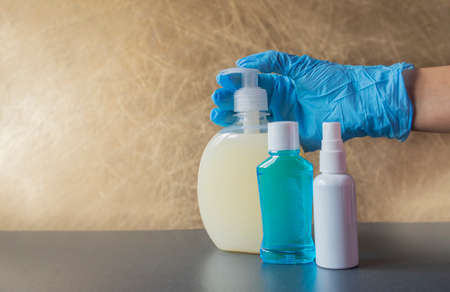 girl holds in her hands bottles with an antiseptic with liquid soap for cleanliness against bacteria in blue rubber glovesの写真素材