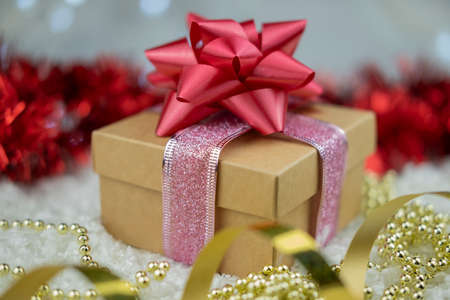 surprise gift with a red bow on the snow on a bokeh background for the new year winter holiday and...