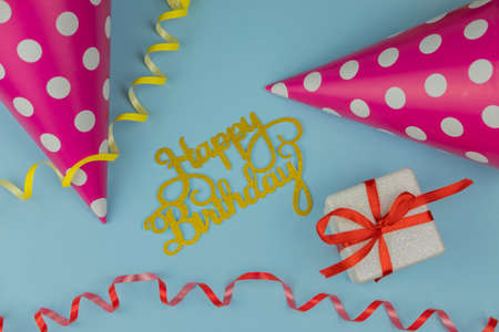 background greeting card for birthday party with a cap a gift and a serpentine on a blue background with the text for the inscriptionの写真素材