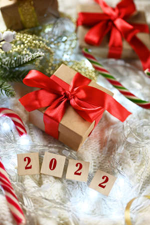 gift boxes on a knitted blanket with a bow with sweets Santa Claus staff with wooden numbers 2022 for new year and christmasの写真素材