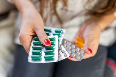 girl holds medicine pills and capsules in her hands for pain relief and treatmentの写真素材