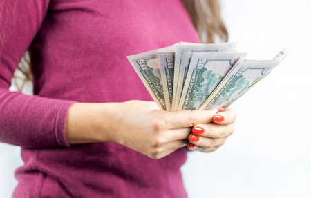 girl holding a pile of wads of money dollar bills to buy or pay
