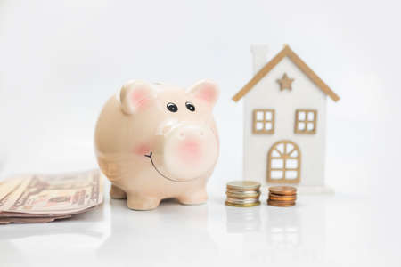 buying and selling real estate in the investment market. piggy bank with coins and dollars with a...