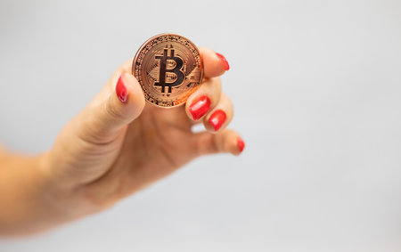 girl holding a metal gold digital internet trend cryptocurrency in her hand on a white backgroundの写真素材