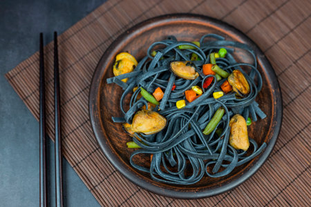 dish noodles black with vegetables and mussels asian food with chopsticksの写真素材