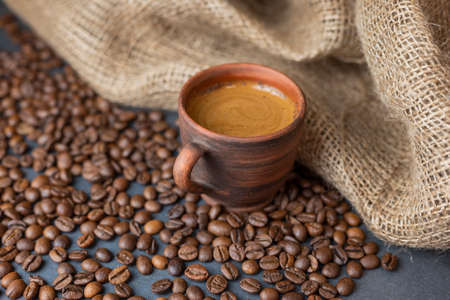 hot delicious aromatic coffee black espresso in a clay cup on a background of coffee beansの写真素材