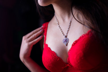 bust breasts of a girl in underwear red corset bra with decoration pendant necklaceの写真素材