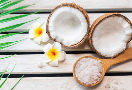sea â€‹â€‹salt in a wooden spoon with coconut for beauty care and mango flowers