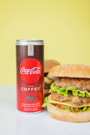 Kiev Ukraine February 20, 2020, burger sandwich hamburger with vegetables meat cutlet with a drink of coca cola in a jar on a yellow background for advertisingのeditorial素材
