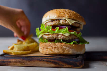 delicious large double burgeon with vegetables cutlet veal meat with lettuce and cheese on a wooden board .Hamburger with friesの写真素材