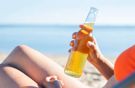 girl in a swimsuit with a bottle of beer on the beach
