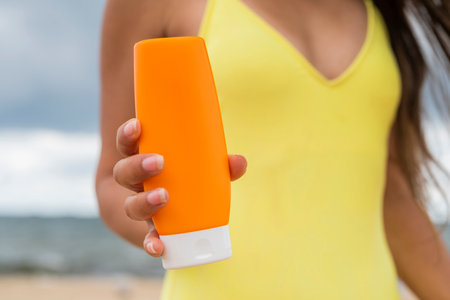 girl in a yellow swimsuit in the summer on the beach with protective sunscreenの写真素材
