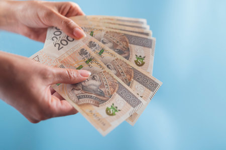 the girl holds in her hands a wallet and zloty paper banknotes for paymentの写真素材