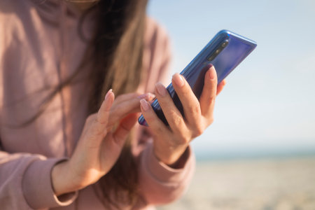 girl holding phone smartphone in hands on the seashore