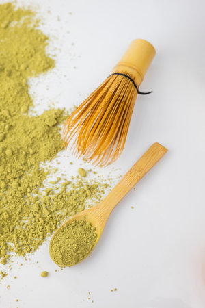 matcha green detox tea scattered with dry wooden spoon and bamboo whisk