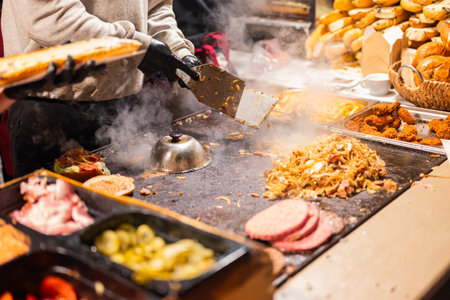 vendor fries meat and sausage on the grill in the city center at the Christmas market in Krakow Polandの写真素材