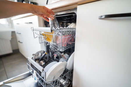 girl cleaning the kitchen putting dishes in the dishwasher for cleanlinessの写真素材
