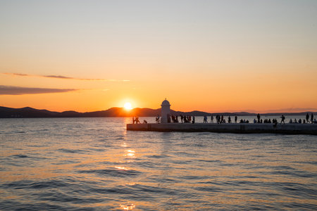 A beautiful sunset on the seafront promenade with a lighthouse landmark in Zadar, Croatia.の写真素材