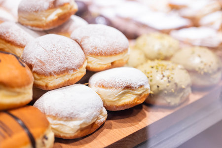 Sweet pastries, donuts with powdered sugar and pistachio cream, on display in a cafeの写真素材