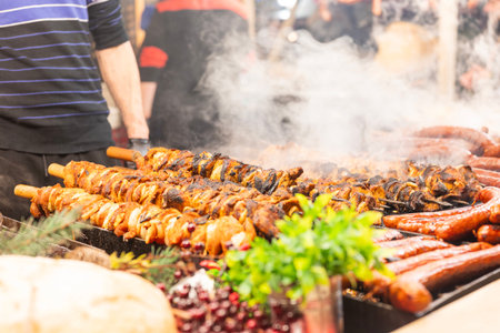 vendor fries meat and sausage on the grill in the city center at the Christmas market in Krakow Polandの写真素材