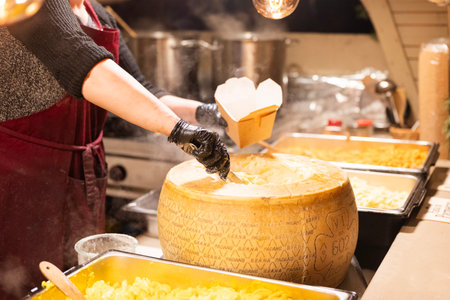 Italian pasta served in a cheese head, a street food item, is served in the city center at the Christmas market in Krakow, Poland.の写真素材