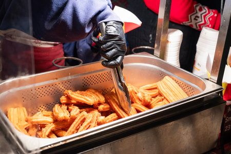 preparing fried sweet churros street food in the city center at the Christmas market in Krakow, Poland.の写真素材