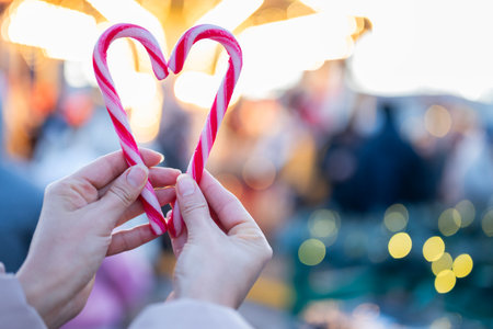 A girl makes a heart out of Santa Claus candies with her hands at the Christmas and New Year's fair.の写真素材