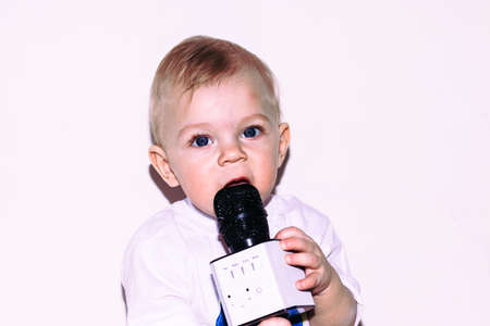 Little boy of 9 months sits on the floor with a microphone.の写真素材