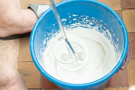 Man stirs putty in a bucket mixerの写真素材