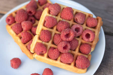 waffles for national day, waffles with raspberries on a wooden background on a blue plate. a place to copy.の写真素材
