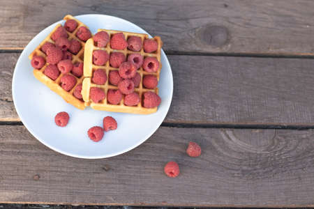 waffles for national day, waffles with raspberries on a wooden background on a blue plate. a place...