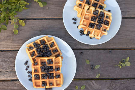 Belgian waffles with blueberries on a wooden background on a plate.の写真素材