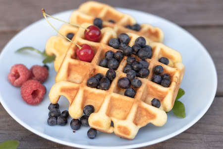 waffles Belgian mix of blueberries raspberries on a wooden background.の写真素材