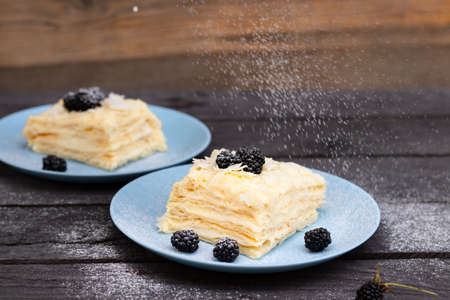 puff pastry with blackberries sprinkled with powdered sugar on a wooden background