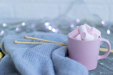 knitting needles, a cup of coffee with pink marshmallows.Christmas lights