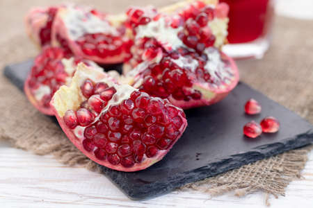 pomegranate fruit open on black slate board, side view, light vintage wooden backgroundの写真素材