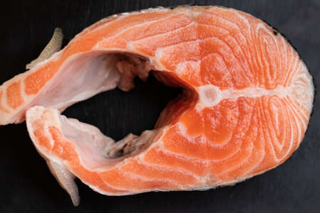 salmon steak on a black slate board on a wooden background viewの写真素材