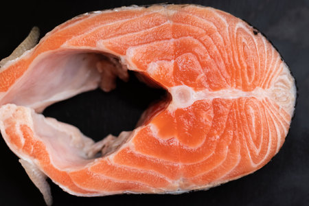 salmon steak close-up view from above on a black boardの写真素材