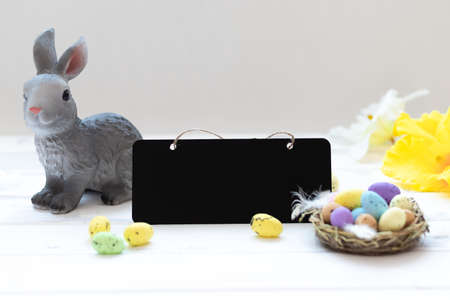 happy easter day, easter bunny and eggs in a nest on a white wooden background, copy space.の写真素材