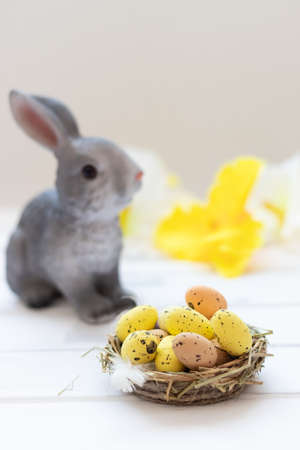 happy easter day, easter bunny and eggs in a nest on a white wooden background,vertikalの写真素材