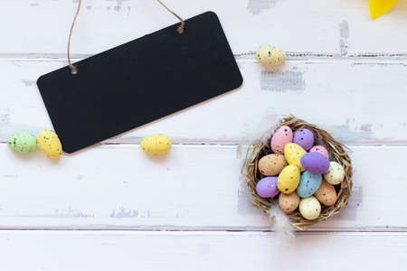 happy Easter, colorful Easter eggs in a nest on a white wooden background. Easter decoration. Space for copyingの写真素材